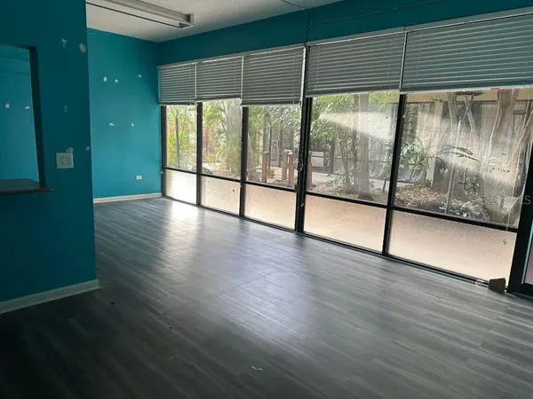 an empty room with wooden floor and windows with curtains