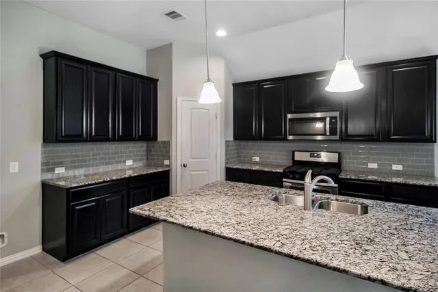 a kitchen with kitchen island granite countertop stainless steel appliances and a sink