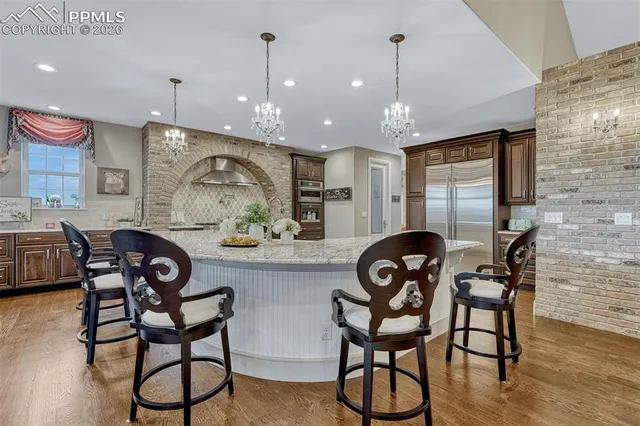 a kitchen with stainless steel appliances granite countertop a dining table chairs stove and cabinets