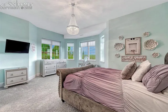 a bedroom with a beds chandelier and a window