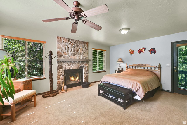 655 Ogden Canyon Road Ogden, UT 84401 - Photo 17 of 50 Stone-surround fireplace with a hearth and mantel, complemented by two windows with wood blinds, a ceiling fan, and a glass-paneled door