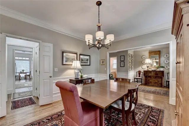 a dining room with wooden floor a chandelier a wooden table and chairs
