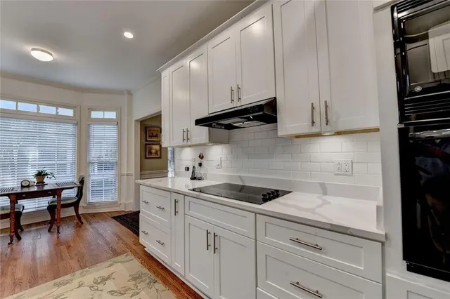 a kitchen with white cabinets and black appliances