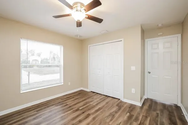 a view of an empty room with window and wooden floor