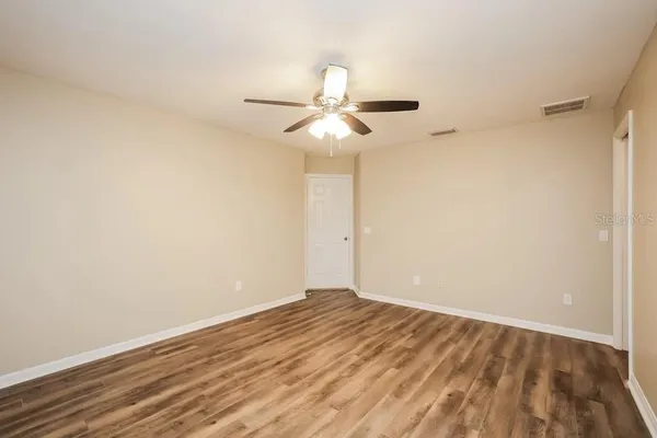 a view of a room with wooden floor and a ceiling fan