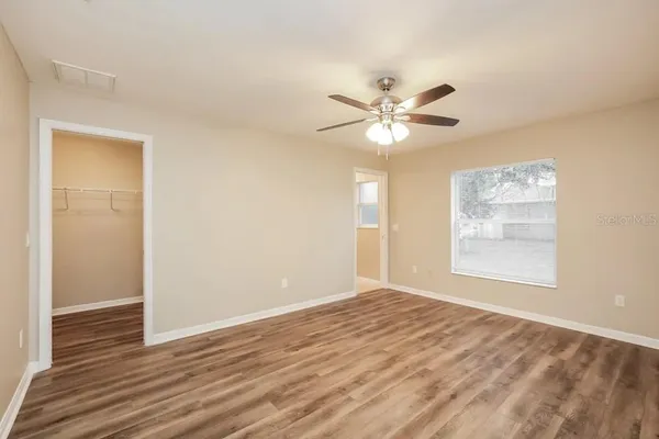 a view of an empty room with chandelier fan and a window