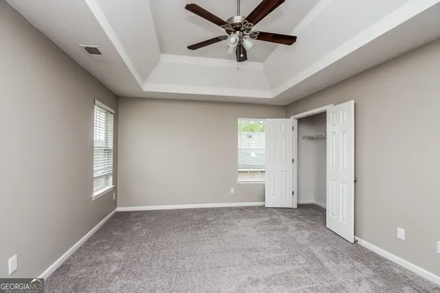an empty room with windows and fan