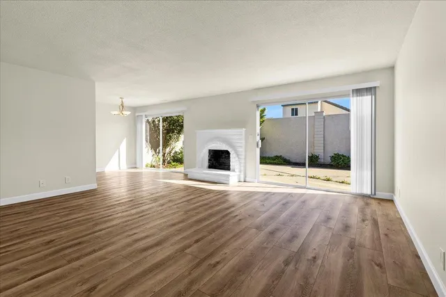 a view of empty room with wooden floor and fireplace
