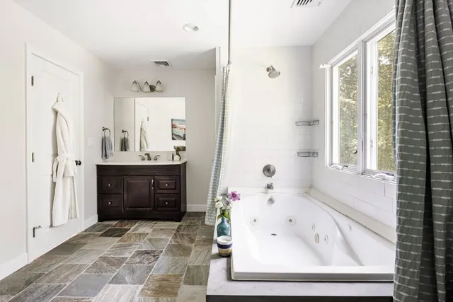 a bathroom with a tub sink and mirror