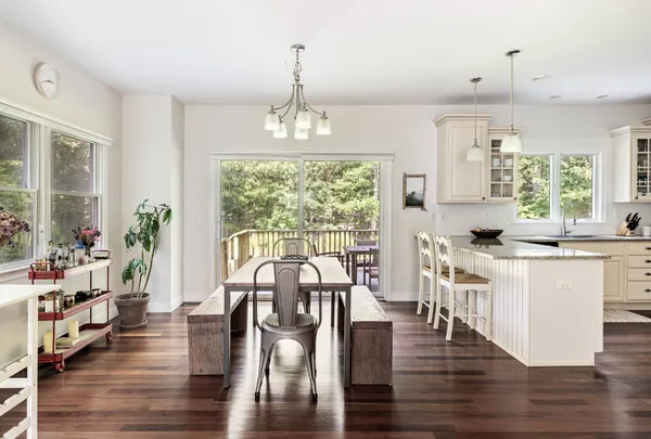 a open dining room with wooden floor kitchen view and a chandelier