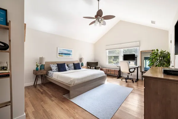 a bedroom with a large bed a chandelier and windows