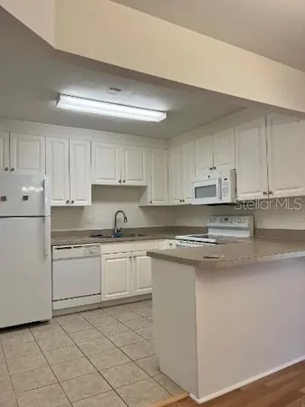 a kitchen with granite countertop white cabinets and white stainless steel appliances