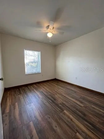 a view of an empty room with wooden floor and a window