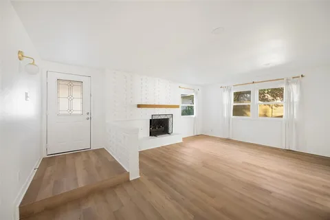 an empty room with windows and fireplace