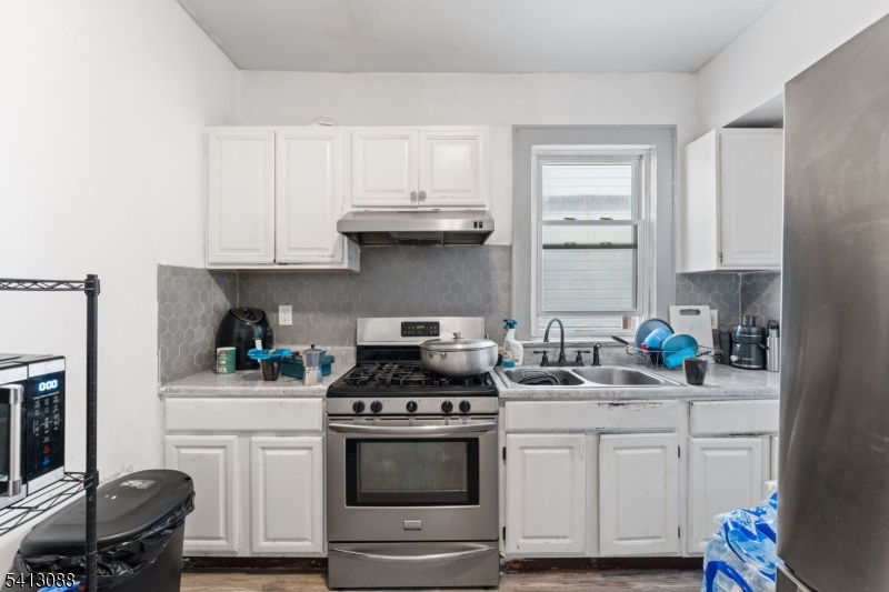 907 Flora Street Elizabeth, NJ 07201 - Photo 15 of 24 a kitchen with stainless steel appliances white cabinets and a stove a sink
