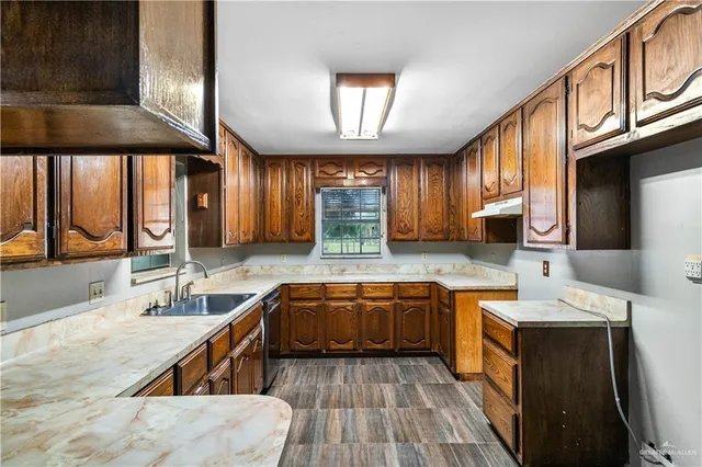 a kitchen with granite countertop a sink a counter space cabinets and stainless steel appliances