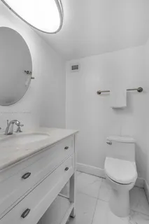 a bathroom with a granite countertop toilet sink mirror and vanity