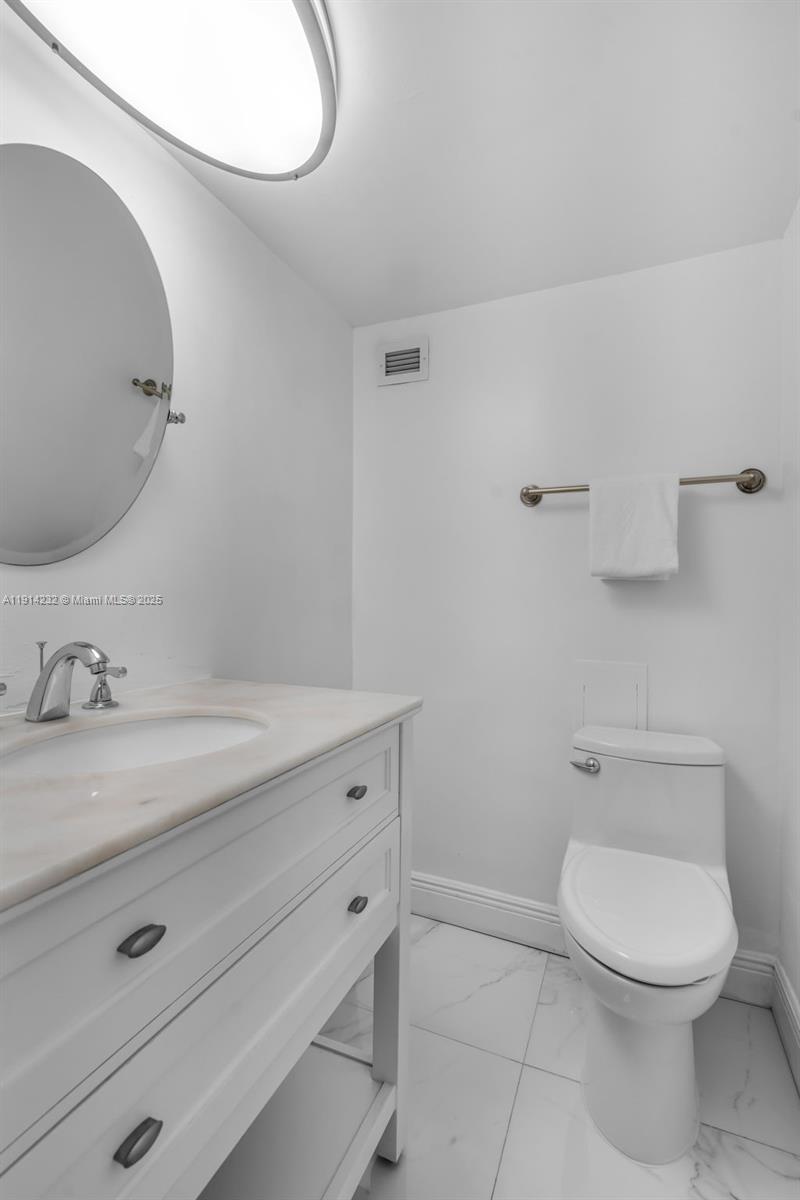 5101 Collins Avenue, Unit 12U Miami Beach, FL 33140 - Photo 8 of 26 a bathroom with a granite countertop toilet sink mirror and vanity
