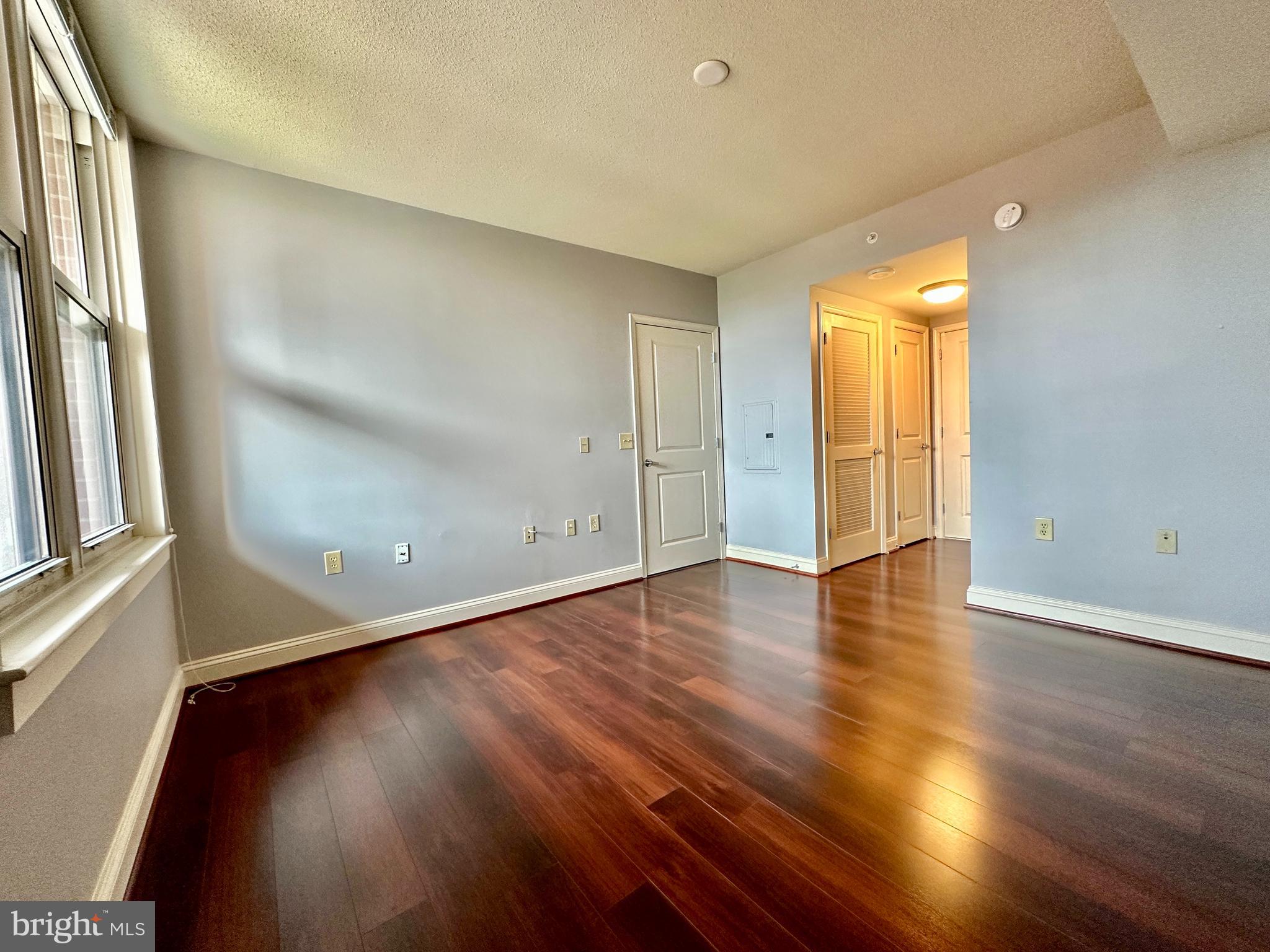 11760 Sunrise Valley Drive, Unit 512 Reston, VA 20191 - Photo 6 of 19 an empty room with wooden floor and windows with curtains