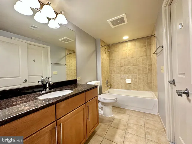 a bathroom with a granite countertop sink a toilet and bathtub