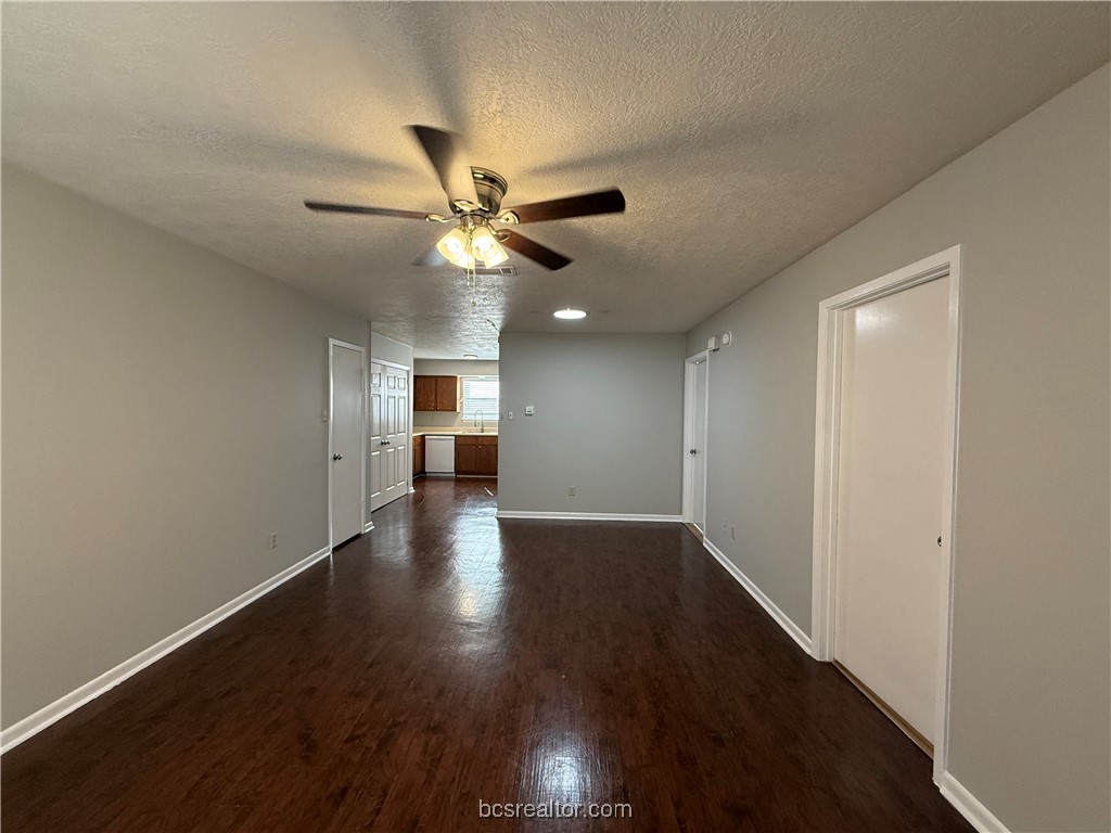 902 Spring Loop, Unit C College Station, TX 77840 - Photo 2 of 11 Unfurnished living room with a textured ceiling, dark wood-type flooring, and a ceiling fan