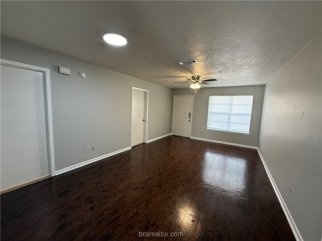 902 Spring Loop, Unit C College Station, TX 77840 - Photo 3 of 11 Spare room with dark wood finished floors and a textured ceiling