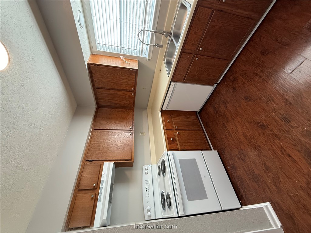 902 Spring Loop, Unit C College Station, TX 77840 - Photo 5 of 11 Kitchen featuring range, a textured ceiling, dark wood-type flooring, white dishwasher, and light countertops