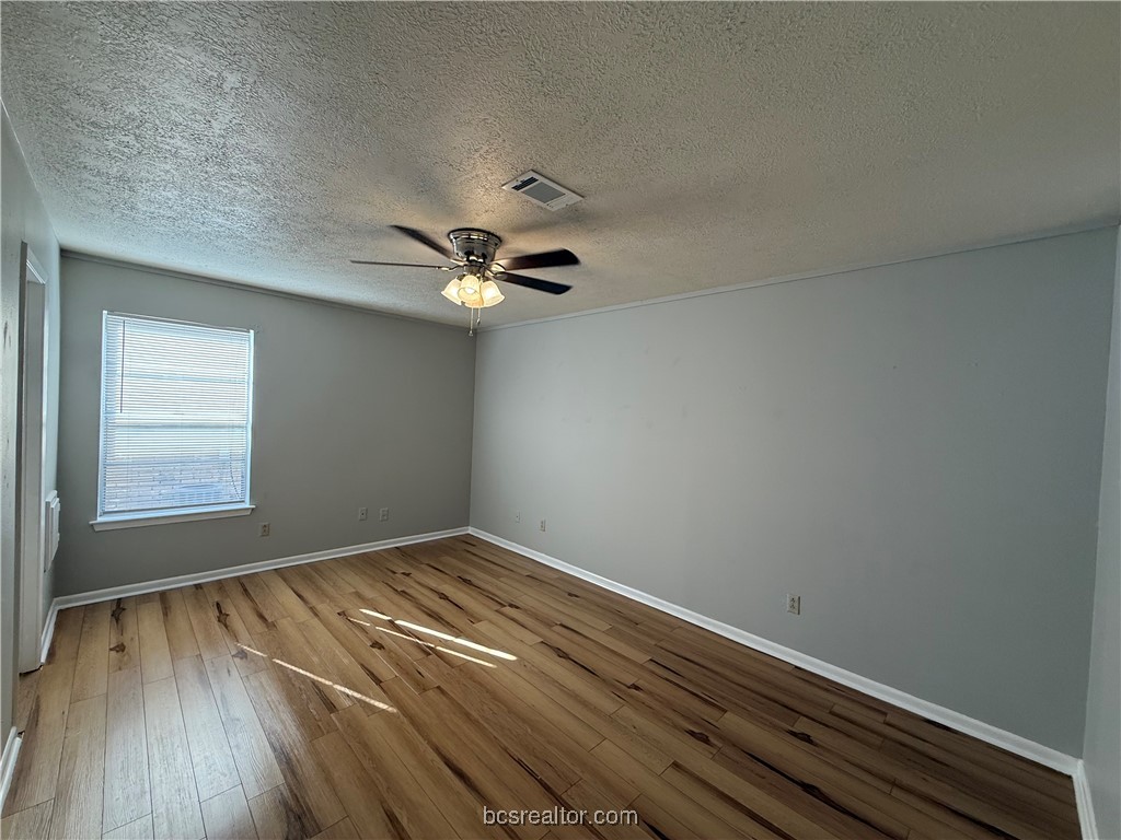 902 Spring Loop, Unit C College Station, TX 77840 - Photo 6 of 11 Empty room featuring hardwood / wood-style flooring, a textured ceiling, and ceiling fan