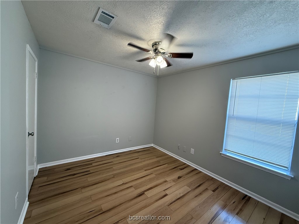 902 Spring Loop, Unit C College Station, TX 77840 - Photo 8 of 11 Spare room with light wood-type flooring, a textured ceiling, and ceiling fan