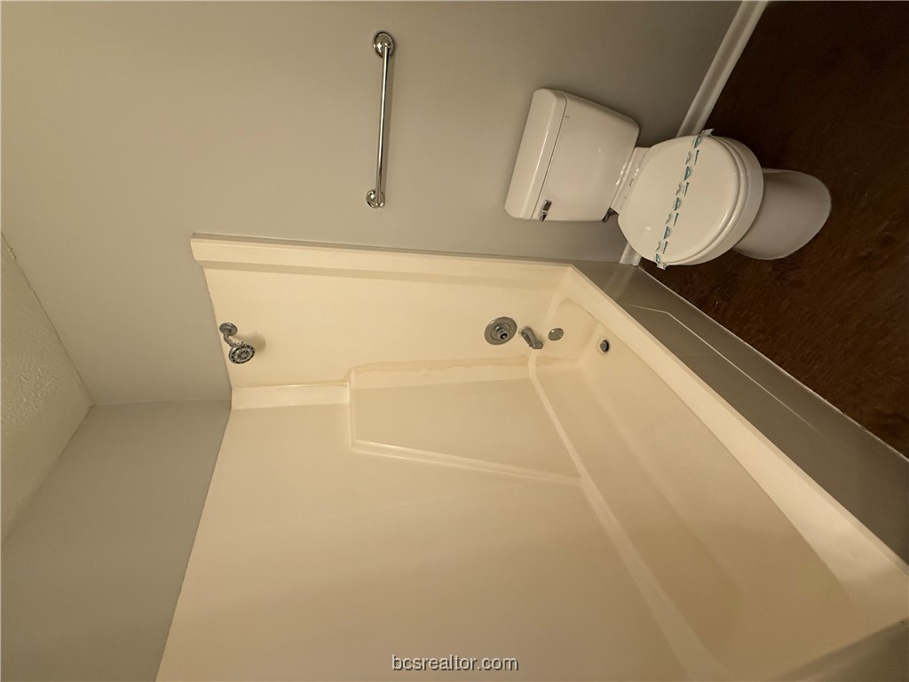 902 Spring Loop, Unit C College Station, TX 77840 - Photo 10 of 11 Bathroom featuring dark wood-style floors, shower / bath combination, and a textured ceiling