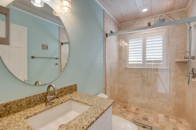 a bathroom with a granite countertop sink a mirror and shower