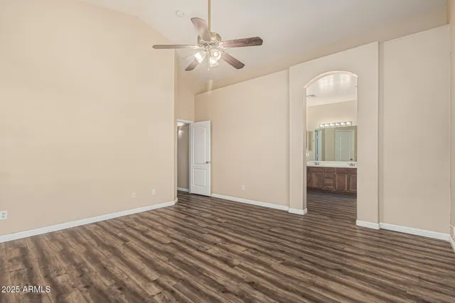 an empty room with wooden floor fan and windows