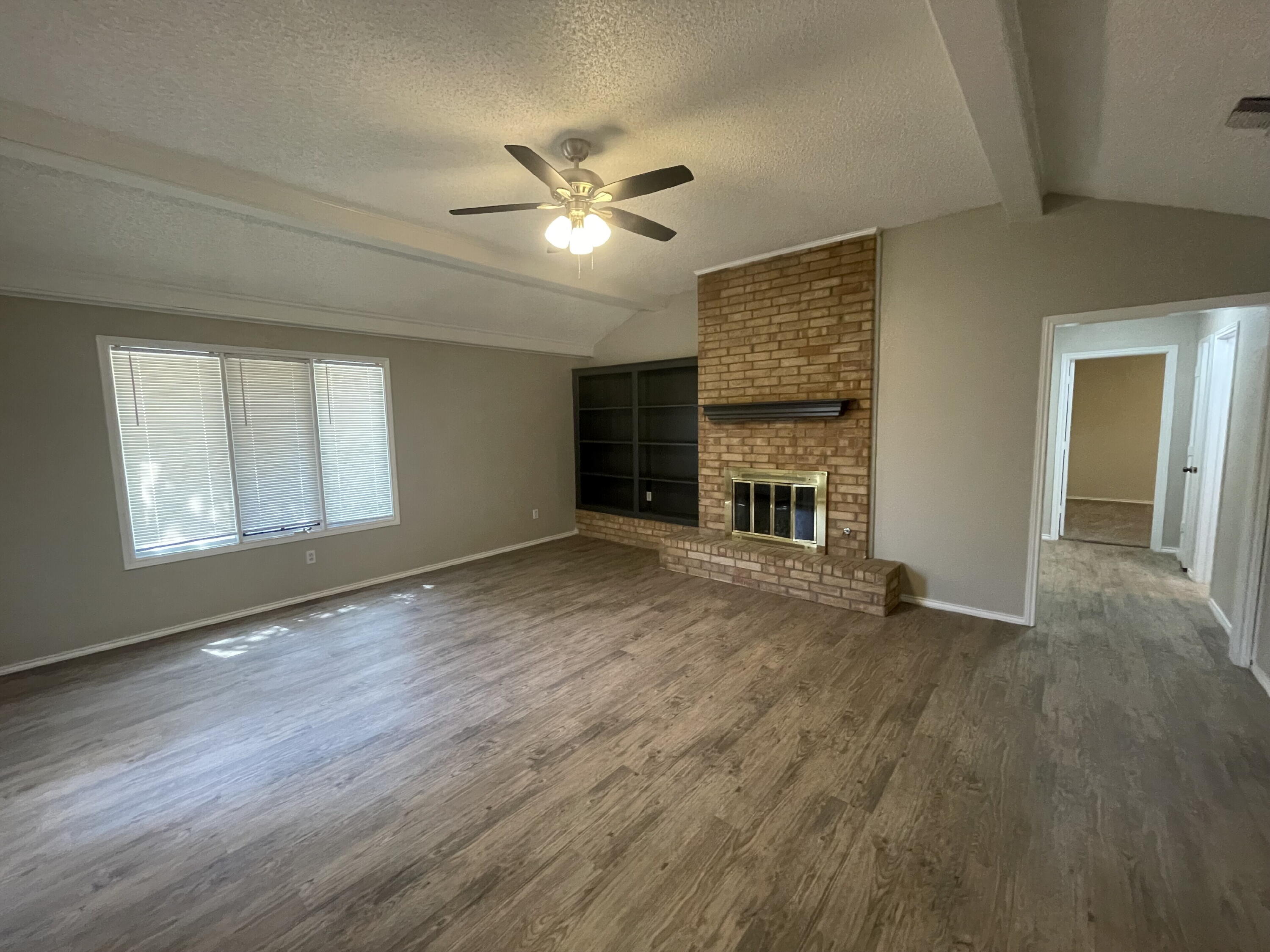 6724 4th Street, Unit A Lubbock, TX 79416 - Photo 2 of 9 a view of an empty room with wooden floor fireplace and a window