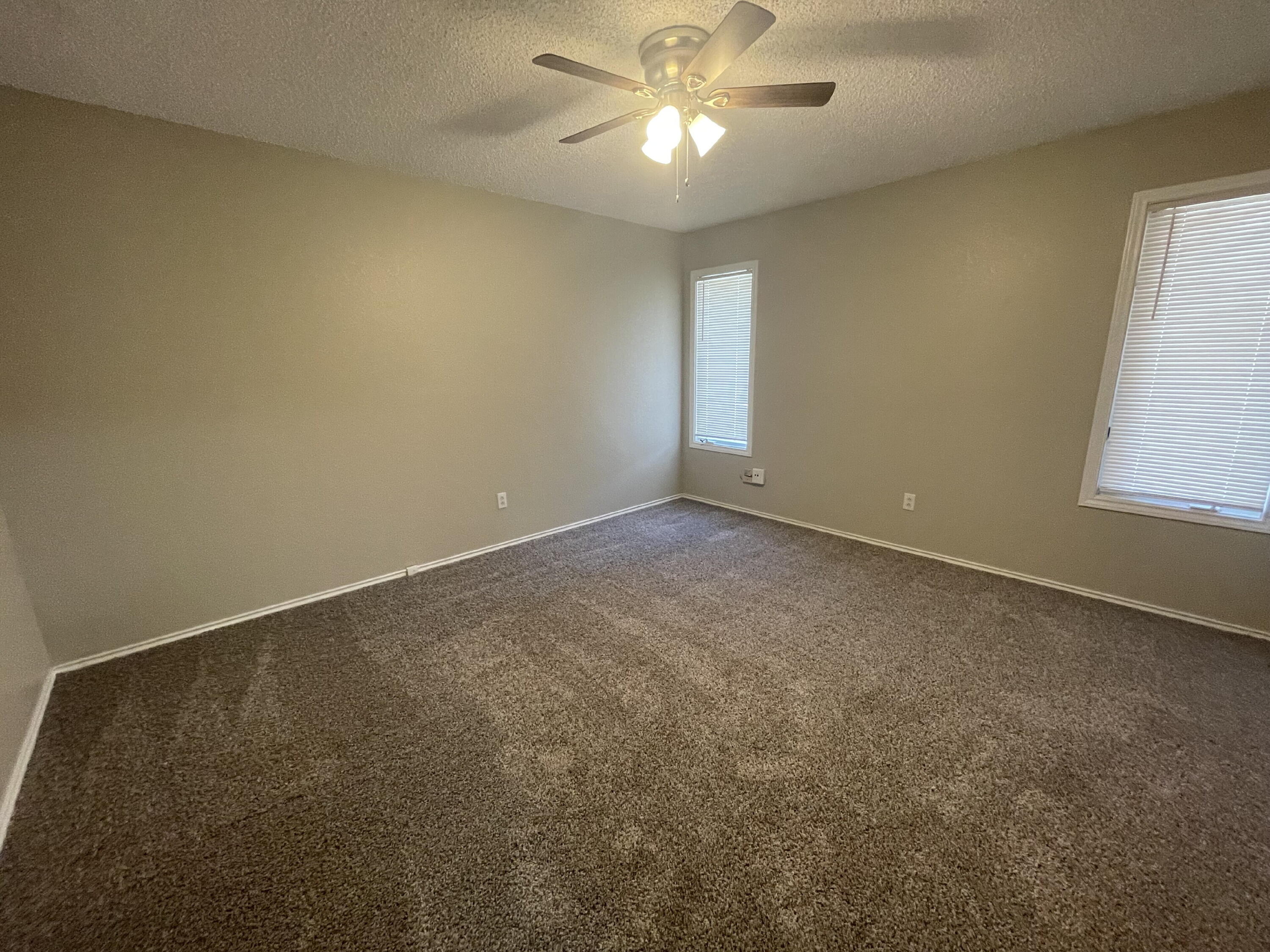 6724 4th Street, Unit A Lubbock, TX 79416 - Photo 5 of 9 an empty room with windows and fan