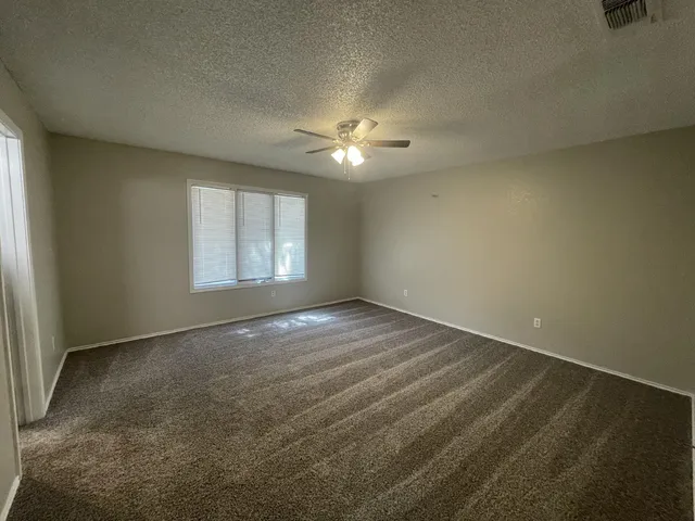 an empty room with windows and fan
