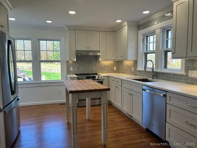 a kitchen with kitchen island granite countertop wooden floors wooden cabinets and stainless steel appliances