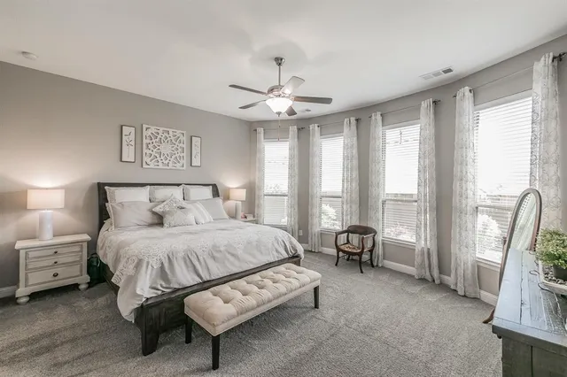 a spacious bedroom with a bed a couch and a large mirror