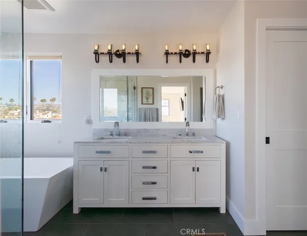 a bathroom with a double vanity sink mirror and bathtub