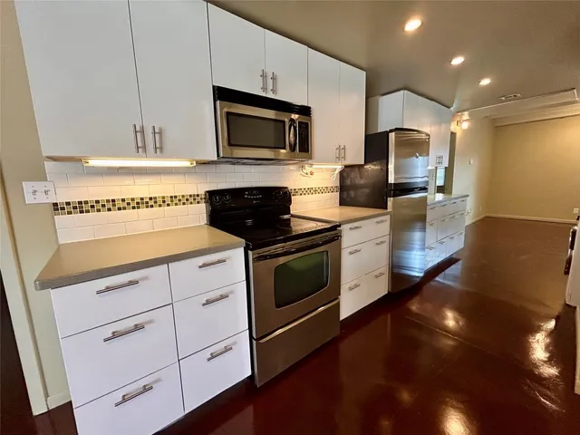 a kitchen with stainless steel appliances kitchen island granite countertop a stove a sink and a microwave