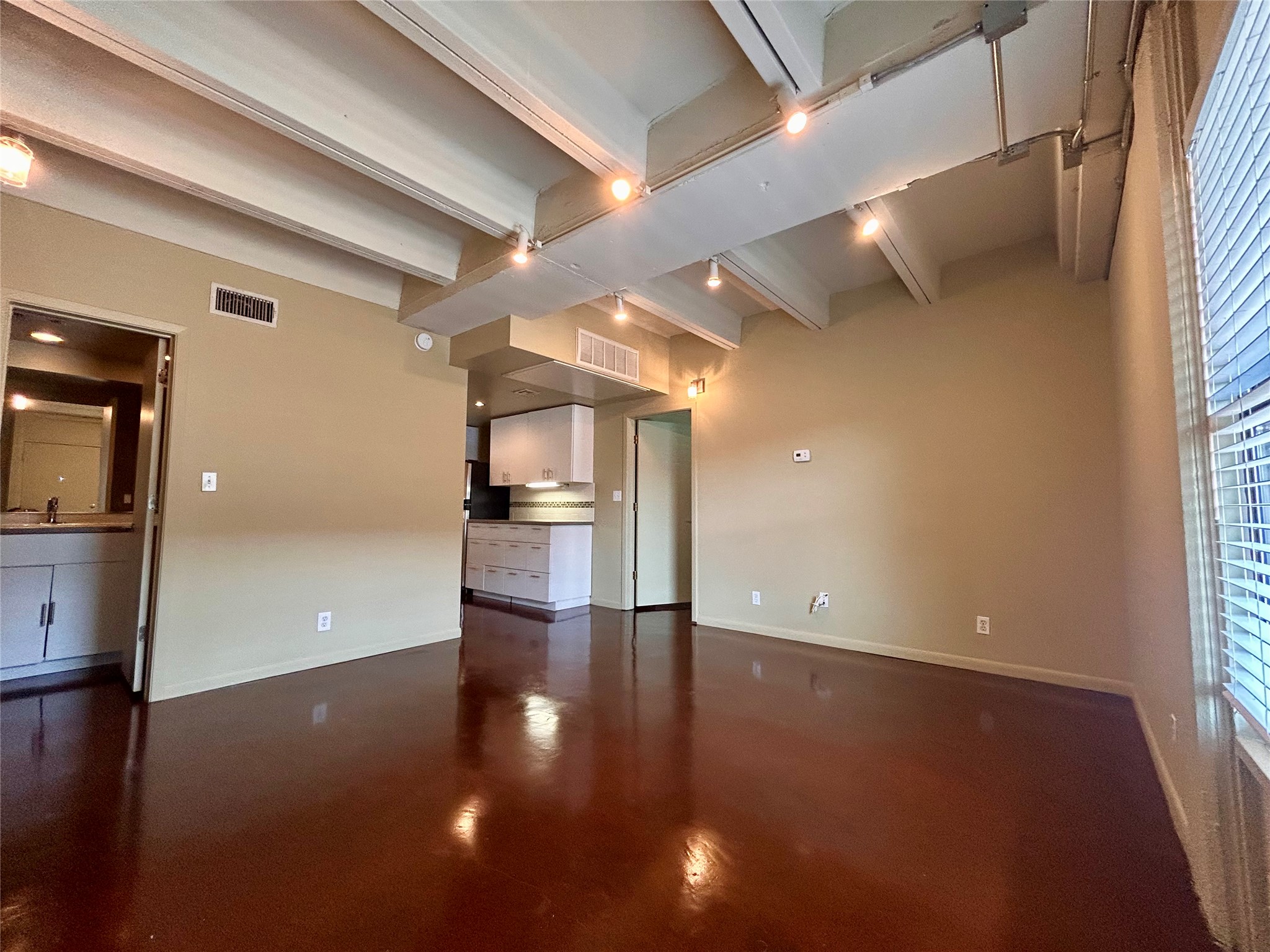 2408 Leon Street, Unit 113 Austin, TX 78705 - Photo 6 of 9 Unfurnished living room featuring beam ceiling and finished concrete flooring