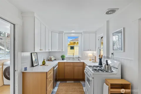 a kitchen with stainless steel appliances a stove a sink a refrigerator white cabinets and wooden floor