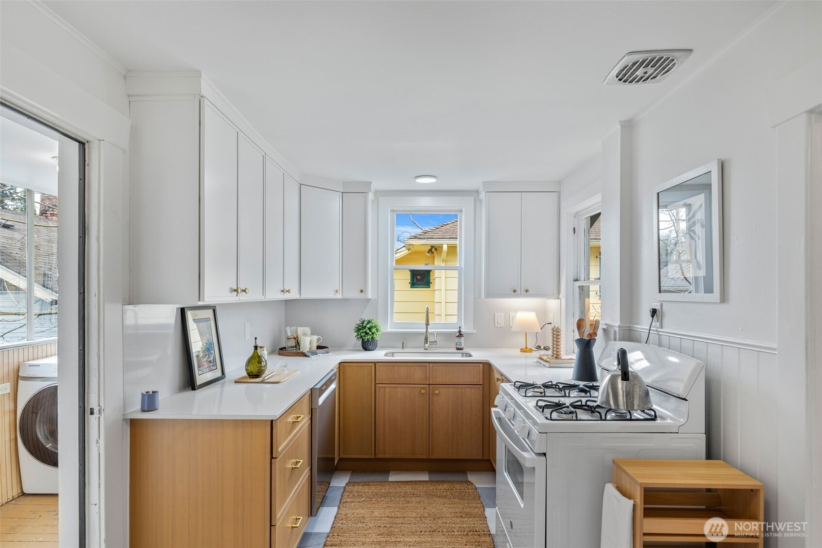 5812 46th Avenue South Seattle, WA 98118 - Photo 12 of 40 a kitchen with stainless steel appliances a stove a sink a refrigerator white cabinets and wooden floor