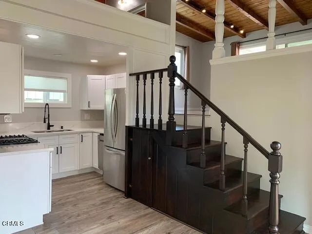 a kitchen with granite countertop a refrigerator a sink and wooden floor