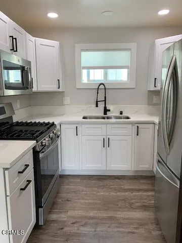 a kitchen with white cabinets appliances and sink