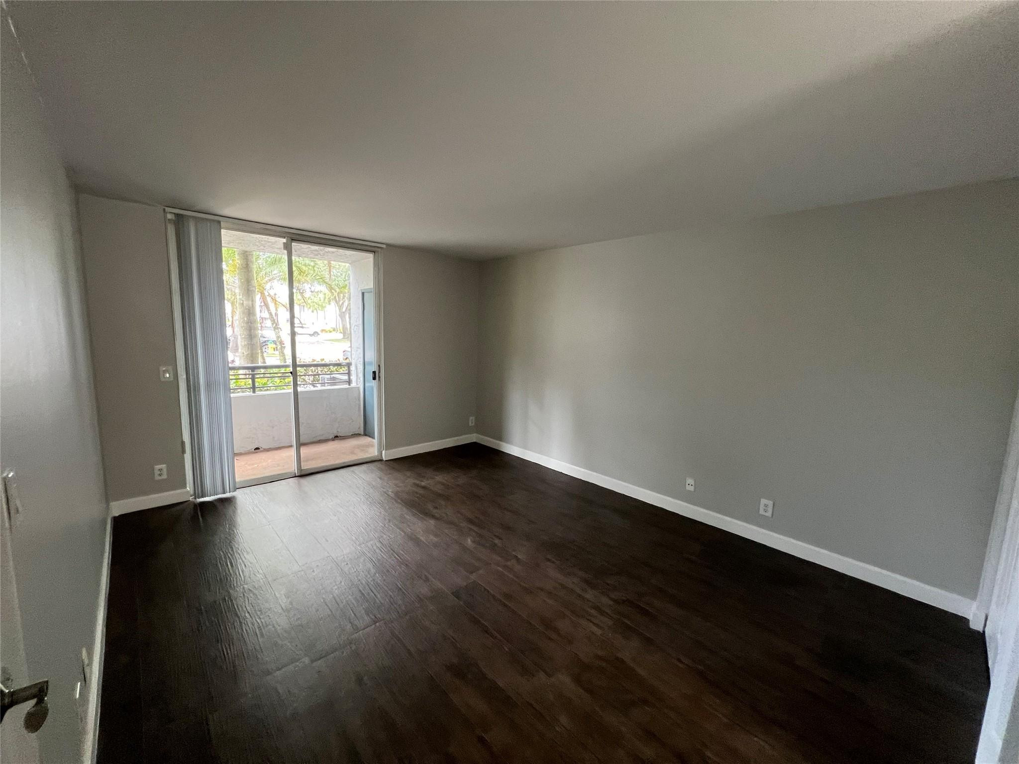 921 Lyons Road, Unit 3105 Coconut Creek, FL 33063 - Photo 15 of 28 a view of an empty room with wooden floor and a window