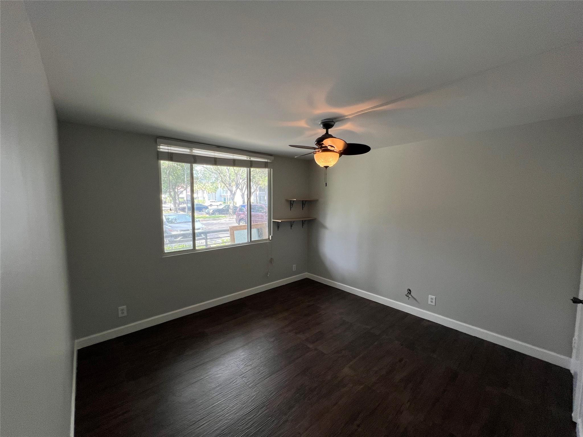 921 Lyons Road, Unit 3105 Coconut Creek, FL 33063 - Photo 22 of 28 an empty room with wooden floor and windows