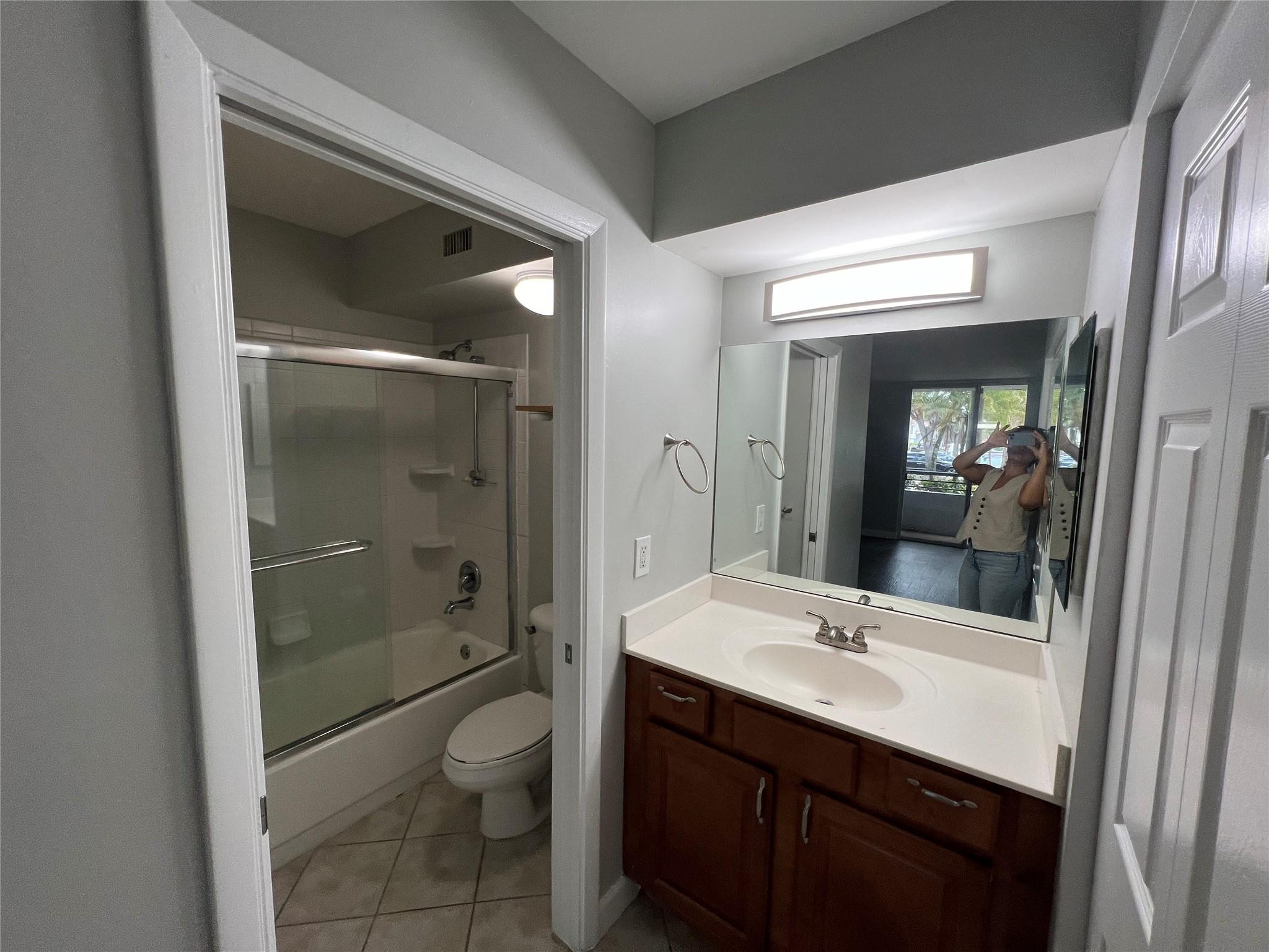 921 Lyons Road, Unit 3105 Coconut Creek, FL 33063 - Photo 6 of 28 a bathroom with a shower sink vanity and mirror