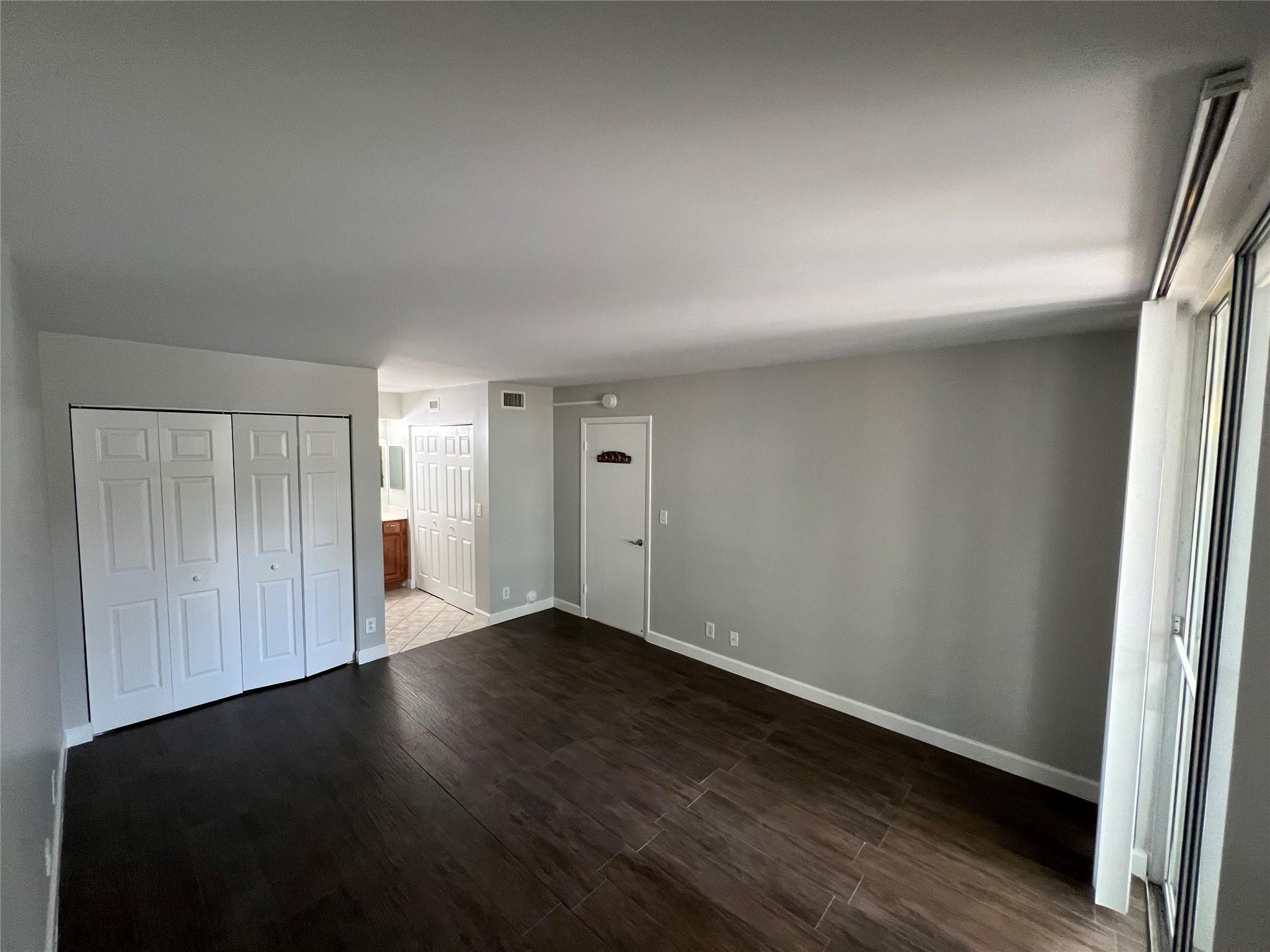 921 Lyons Road, Unit 3105 Coconut Creek, FL 33063 - Photo 8 of 28 an empty room with wooden floor and windows