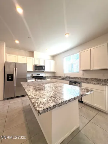 a large kitchen with granite countertop a stove top oven a sink a counter space and cabinets