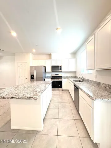 a kitchen with kitchen island granite countertop a sink and a stove